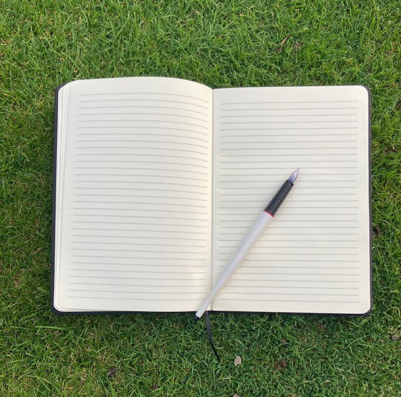 Open notebook with horizontally lined pages. There is a pen on it.